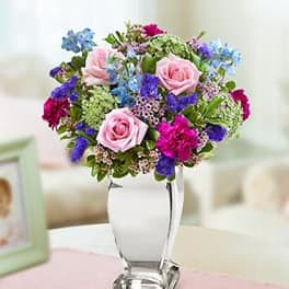 Pink roses and colorful mixed flowers in a clear glass vase