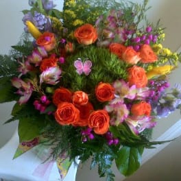 Bouquet of orange roses and mixed purple flowers with a butterfly pick