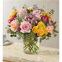 Bouquet of pink and yellow roses in a clear glass vase