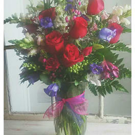 Bouquet of red roses and purple flowers in a glass vase