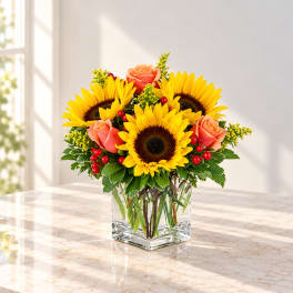 Sunflower and peach rose arrangement in a clear square vase