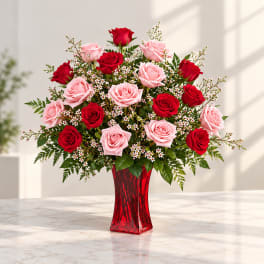 Red and pink roses arranged in a red glass vase