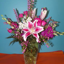 Pink and white lilies with roses in a glass vase