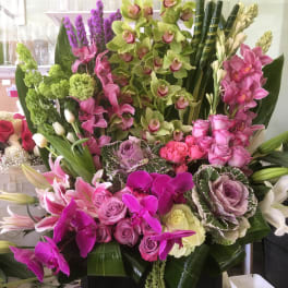 Large mixed floral arrangement with orchids, roses, lilies, and cabbage roses