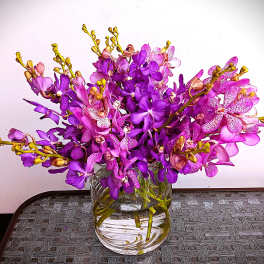 Purple orchids arranged in a clear glass vase