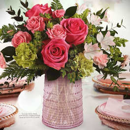 Pink roses and pale flowers arranged in a textured pink vase