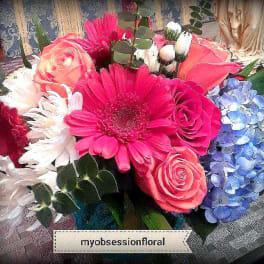 Mixed bouquet with pink gerbera daisies, roses, and blue hydrangeas