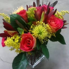 Bouquet of pink roses and yellow spider mums in a clear vase