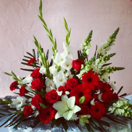 Red and white floral arrangement with roses, lilies, and gerbera daisies