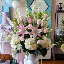 Large pink lily and rose arrangement in a white vase