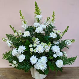 White floral arrangement in a textured white vase with fern accents