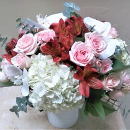 Bouquet of pink roses, white hydrangea, and red alstroemeria in a white vase