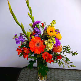 Colorful mixed bouquet in a clear glass vase with tall green spikes