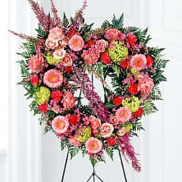 Heart-shaped floral standing spray on an easel with pink and red blooms