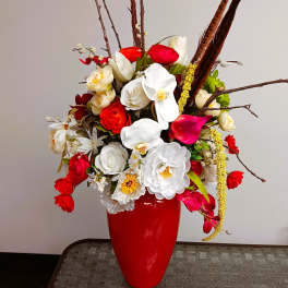Red vase with a mixed bouquet of white, red, and pink flowers