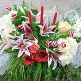 Floral arrangement with lilies, roses, and red candles