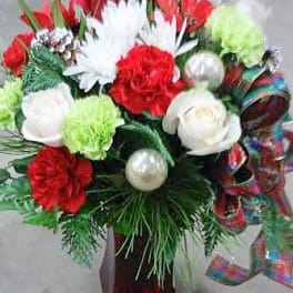 Red and white floral arrangement with ornaments and ribbon in a vase