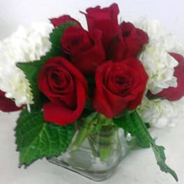 Red roses and white flowers arranged in a clear glass vase