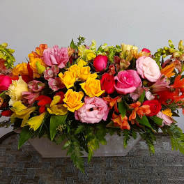 Long low arrangement of multicolored roses and alstroemeria in a rectangular container