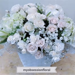 White and pale pink rose bouquet in a white basket