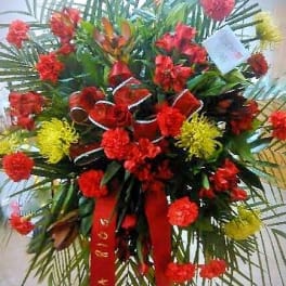 Tall red and yellow floral standing arrangement with ribbon streamers