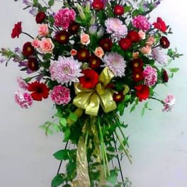 Tall standing floral spray with red, pink, and lavender blooms