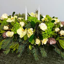White floral centerpiece with candles and pine greenery