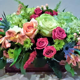 Low floral centerpiece with pink and green roses in a rectangular container