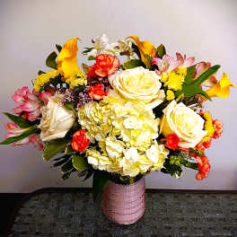 Mixed bouquet of roses, hydrangea, calla lilies, and alstroemeria in a pink vase