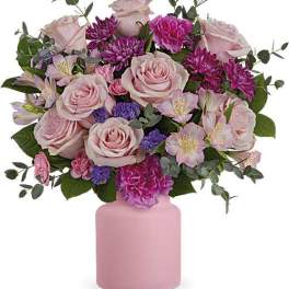 Pink roses and purple flowers arranged in a pink vase