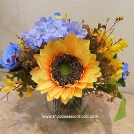 Sunflower bouquet with blue and yellow flowers in a glass vase