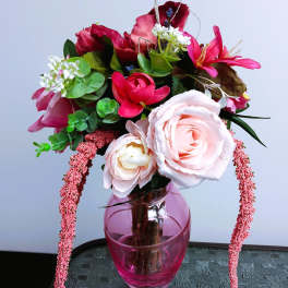 Pink and red floral arrangement in a pink glass vase
