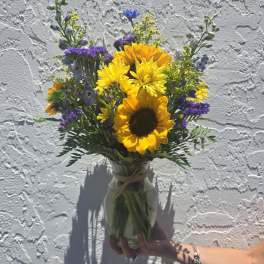 Sunflower bouquet in a glass vase with purple and yellow accents