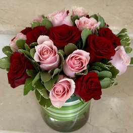Pink and red roses arranged in a striped glass vase