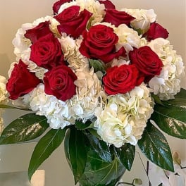 Arrangement of red roses and white hydrangeas in a clear glass vase