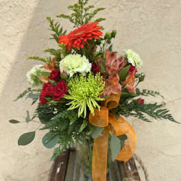 Mixed bouquet in a glass vase with red, green, and peach flowers