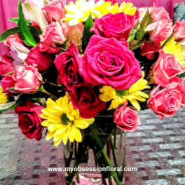 Bouquet of pink and red roses with yellow daisies in a glass vase