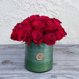 Red roses arranged in a green cylindrical vase