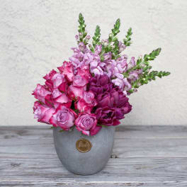 Pink and purple flowers arranged in a gray vase