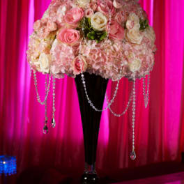Pink and white rose arrangement in a tall black vase with hanging crystal strands