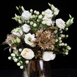 White roses and berry sprigs arranged in a glass vase