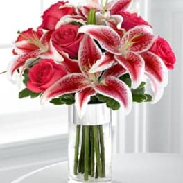 Pink roses and stargazer lilies in a clear glass vase