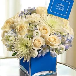 Cream and pale blue bouquet in a blue vase with a card