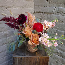 Mixed bouquet of roses and pale pink blooms in a ceramic vase