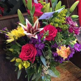 Mixed bouquet of roses, lilies, and chrysanthemums in a glass vase