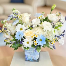 White and blue mixed bouquet in a square glass vase