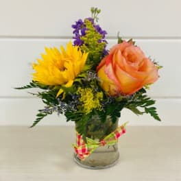Small bouquet with a yellow sunflower and peach rose in a glass vase