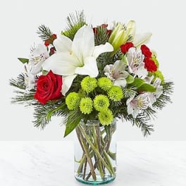 Bouquet of white lilies, red roses, and green pompons in a glass vase