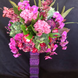 Pink and purple floral arrangement in a wrapped rectangular vase