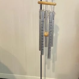 Hanging metal wind chime with silver tubes and a wooden top